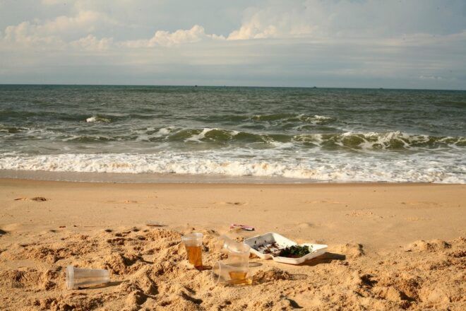 A coast with trash in the sand.