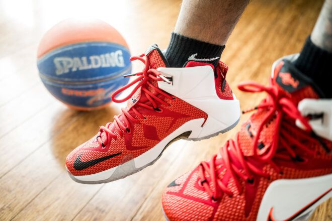 A pair of red sneakers next to a basketball.