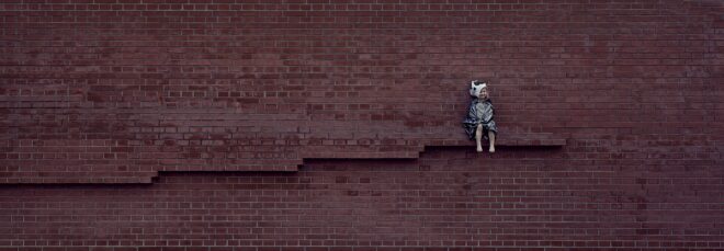 A wall with a little girl sitting on a ledge in-bedded in the wall