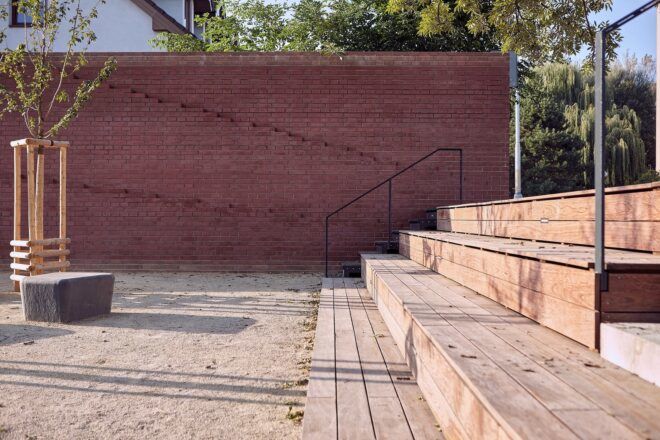 A wooden seating and steps area against a red wall
