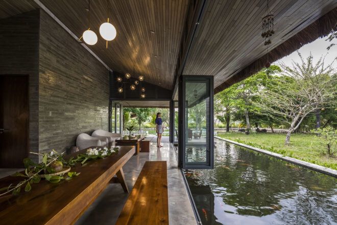 A living room area opens up to a river built into the design