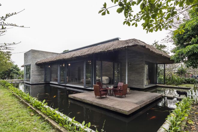 A low wooden house in Vietnam surrounded by a moat of water