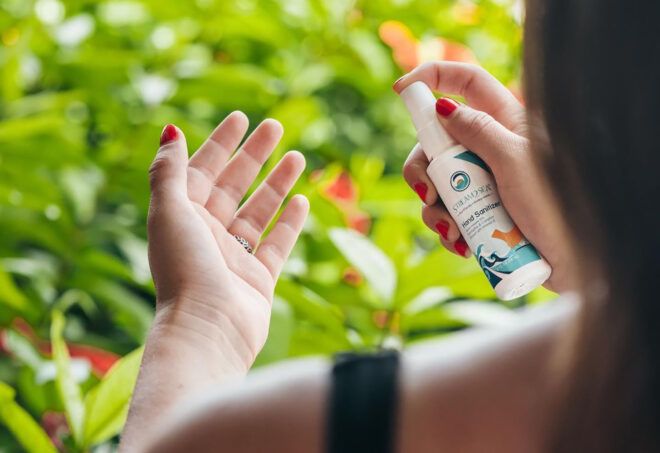A person spraying a reef-safe sunscreen product into their hand.