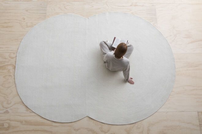 A person sits on a Venn diagram shaped gray rug