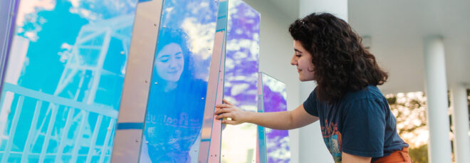 A person touching the TIDAL sculpture which look like rectangular holographic blocks