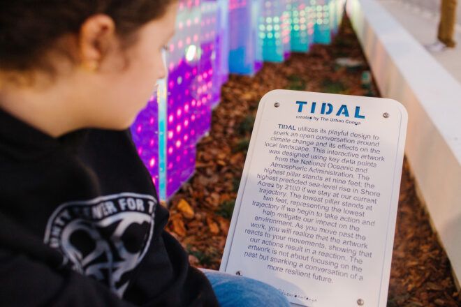 A person reading a sign that is titled Tidal