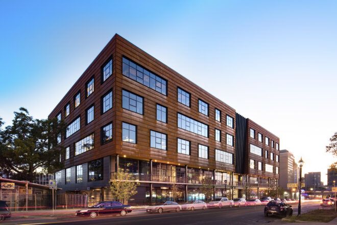 A large brown business building with multiple windows and floors sits at an intersection