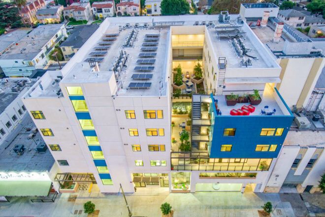Birds eye view of the courtyard building. Various terraces and garden spaces can be seen and the roof features solar panels and other machinery