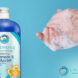A blue bottle of shampoo/body wash to the left of a pair of sudsy hands.