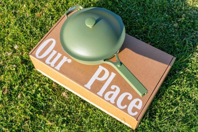 A green pan sits on a cardboard box that reads Our Place on the grass