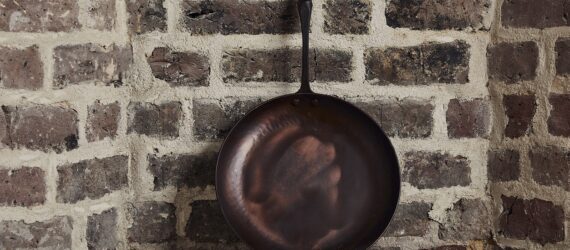 A cast iron pan leaning against a brick wall