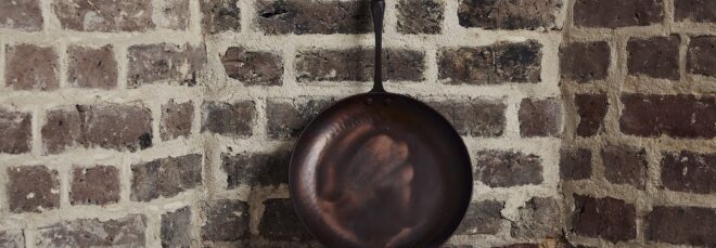 A cast iron pan leaning against a brick wall