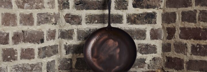 A cast iron pan leaning against a brick wall