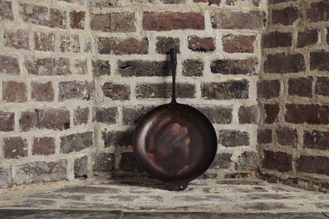 A cast iron pan leaning against a brick wall