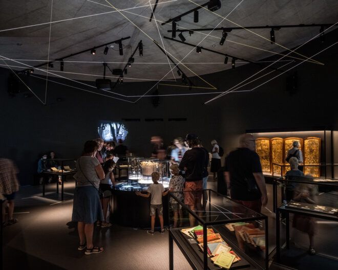 The inside of a museum is dimly lit with display cases throughout the floor