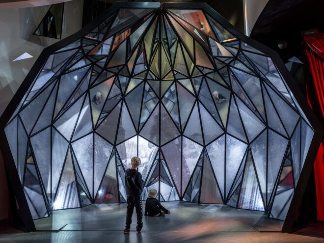 A person stands in front of a orb-shaped structure full of holographic panels
