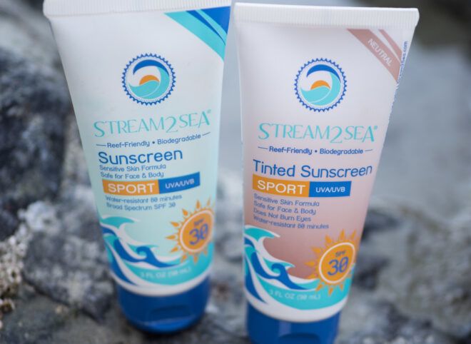 Two tubes of reef-safe sunscreen on the beach.
