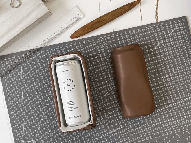 A brown container split in half. One side has it opened up with a white can inside of it while the other side is flipped so you only see the brown exterior. They both lay on a work table
