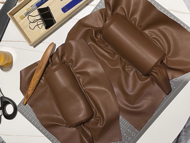 Two brown cylinder figures laying on that same color fabric at a work table