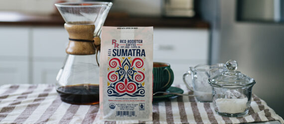 A kitchen scene. At the table is a Red Rooster Coffee bag with a coffee pour over set