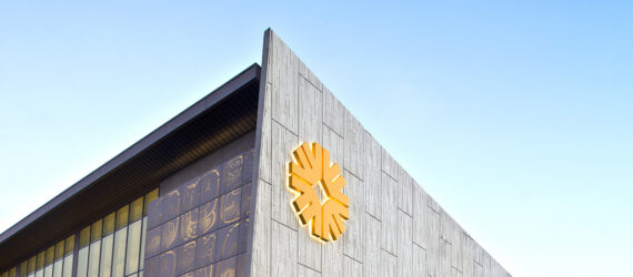 A grey metal building with a yellow symbol that looks like a flower