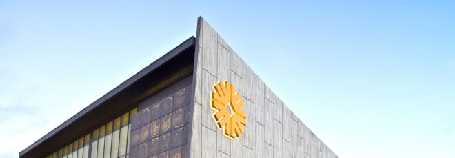 A grey metal building with a yellow symbol that looks like a flower