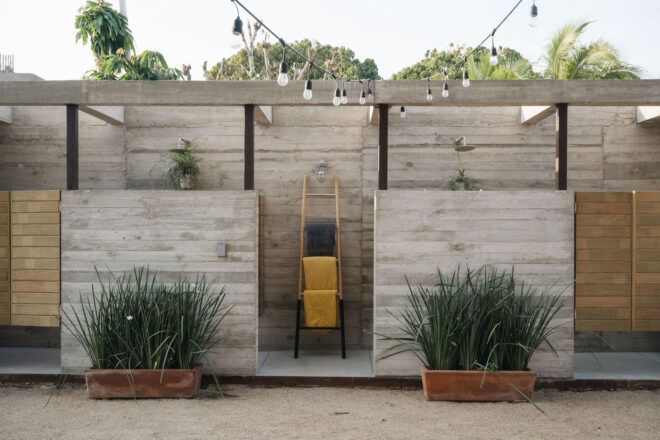 An outdoor shower area is built of wood and decorated with planters