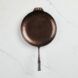 A copper-color cast iron pan sits on a white surface shot from above