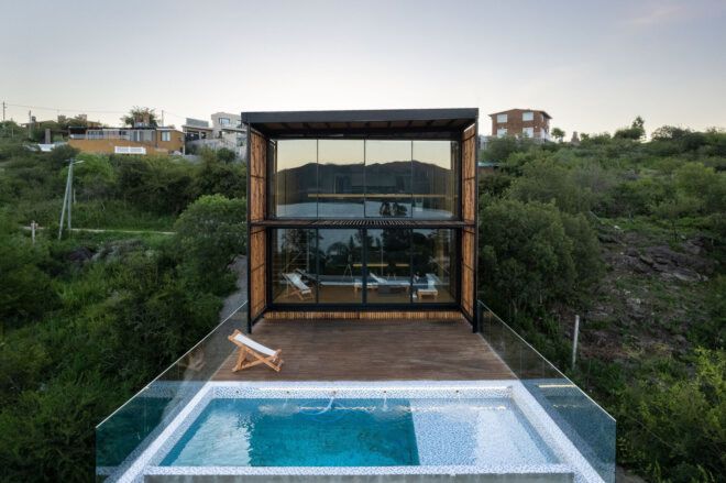 A rectangle pool is connected to a square wooden house
