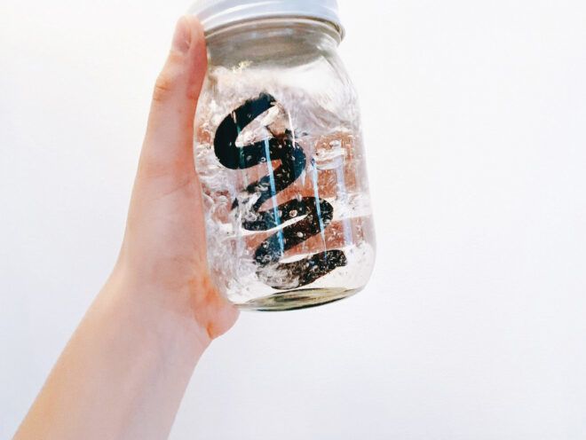 A clear glass jar with a black squiggly inside it