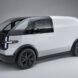 A white Canoo van vehicle sits in an empty room