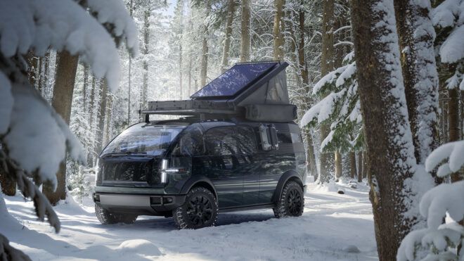 A Canoo electrical vehicle with a camper on the roof sitting in a snowy forest