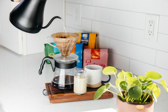 A hot water cooker with water being poured into a pour-over