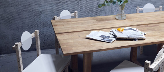 A wooden long rectangle table with chairs gathered around it