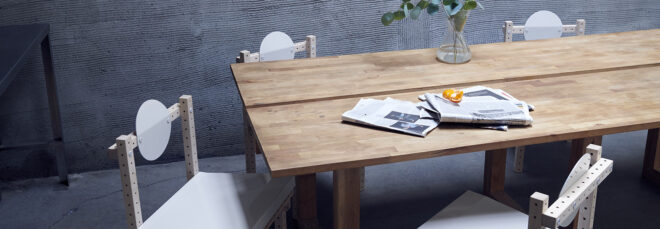 A wooden long rectangle table with chairs gathered around it