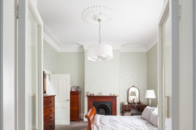 A bedroom with a white lamp hanging from the ceiling