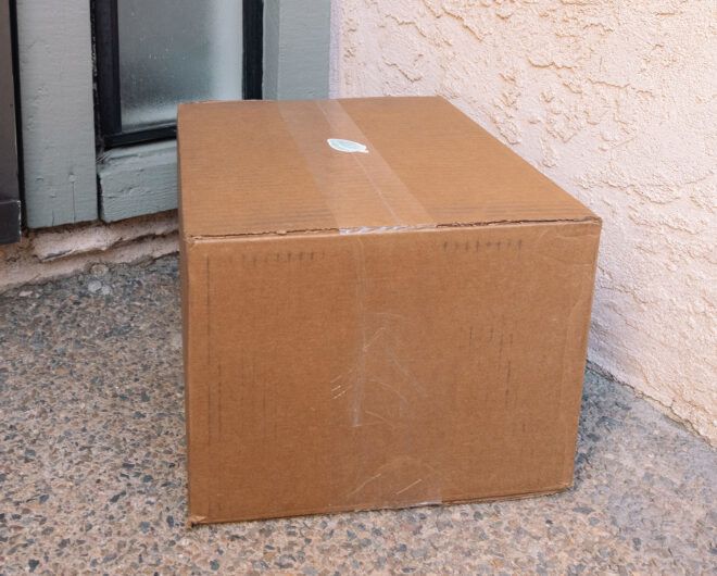 A cardboard brown box with a sticker of a leaf on it