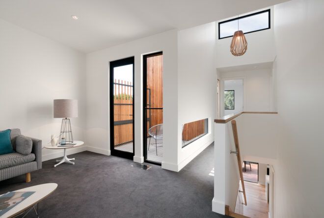 An upstairs room with gray carpet and a staircase leading down