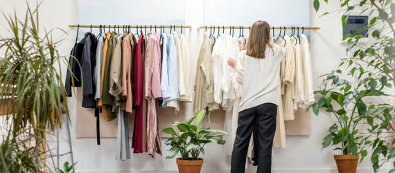 A woman turned toward a rack of clothes shopping
