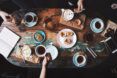 A table spread filled with cups of coffee, plate of pastries and utensils