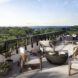 Exterior balcony space has a firepit with white chairs surrounding it