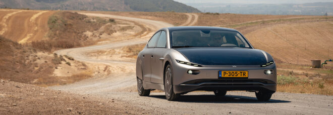 A gray EV driving in a dirt area