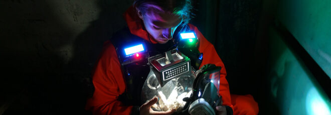 A man with his suit lit up to showcase the mealworms strapped to his chest