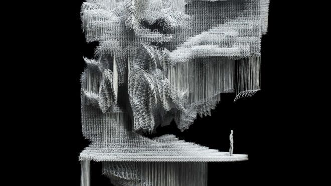 An up-close image of a fibrous sculpture with a miniature human standing at the edge of it