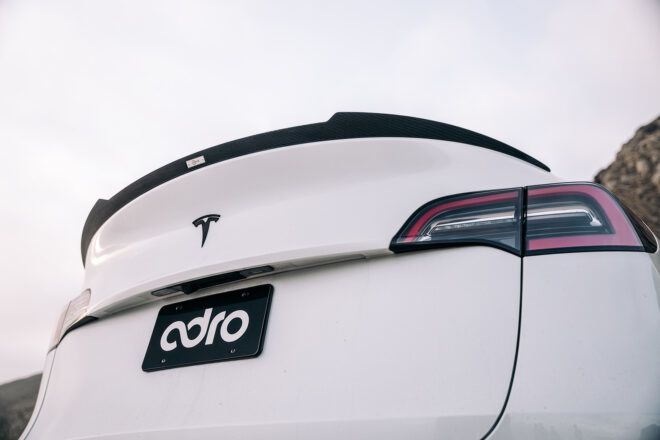 The back of a Tesla white car with the license plate reading ADRO