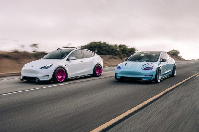Two electric vehicles down a highway, one white and one light blue