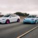 Two electric vehicles down a highway, one white and one light blue