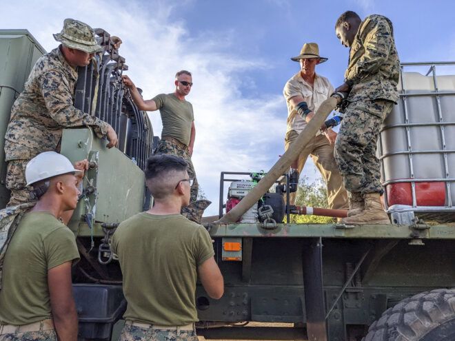 Men in military uniform carrying tiles off of a truck