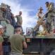 Men in military uniform carrying tiles off of a truck