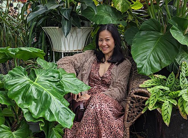 An Asian woman sitting in the middle of full of houseplants